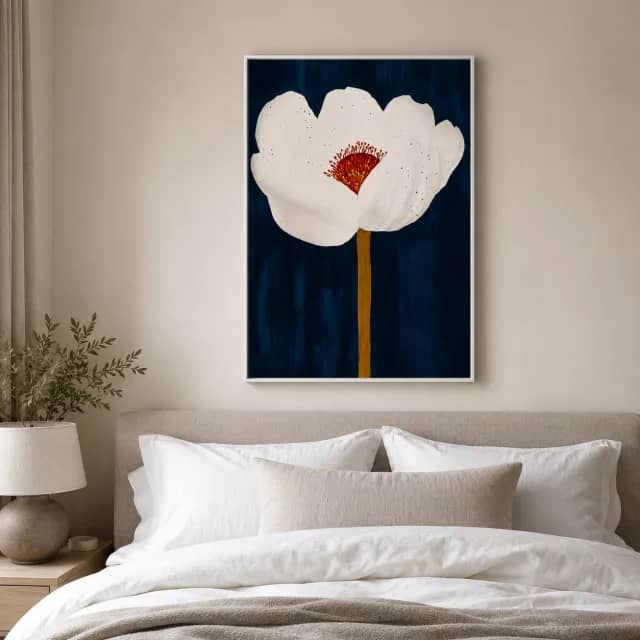 White flower artwork in a white floater frame above a calm bed with light bedding