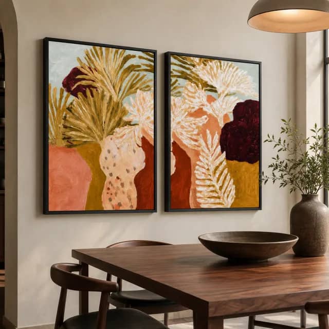 Two botanical panels in black frames above a modern dining corner with warm wood tones