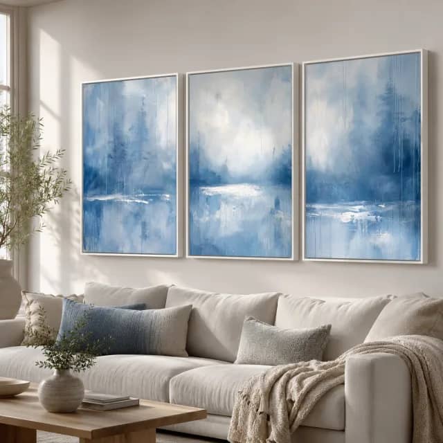 Still Blue Mist three white-framed canvas panels above a light sofa in a living room