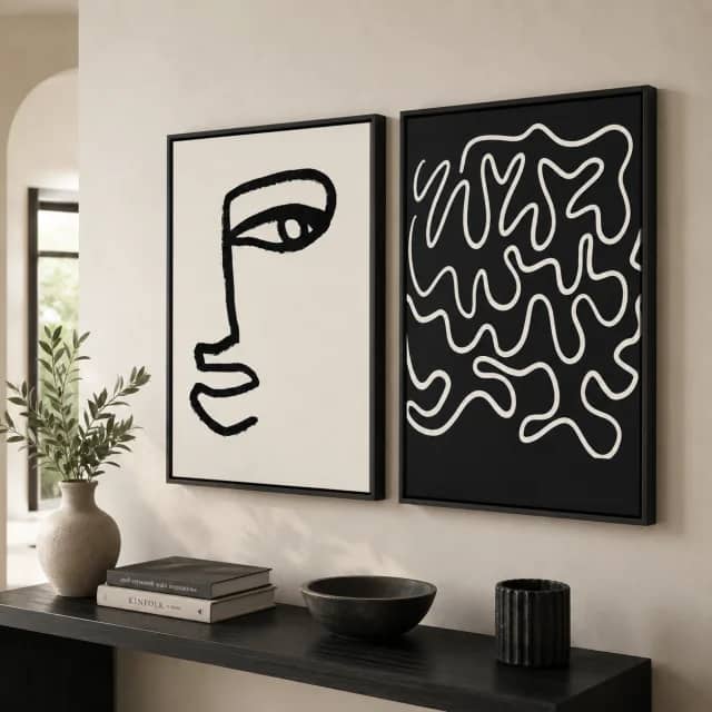 Two black and white abstract canvases above a light sofa in a calm living room