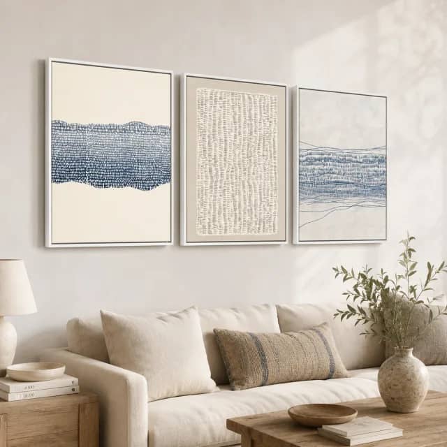 Indigo Expanse three-panel set in white frames above a cream sofa in a calm living room