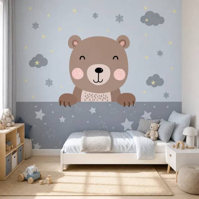 Bear and stars mural behind a white toddler bed in a bright kids bedroom